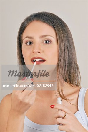Female young adult applying lip gloss