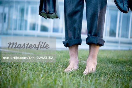 Businessman's bare feet on grass outside of office building