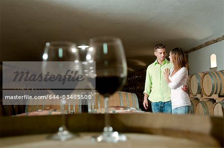 Couple in a wine cellar with glasses of red wine