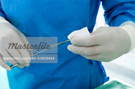 Close up of surgeon with forceps and gauze in his hands