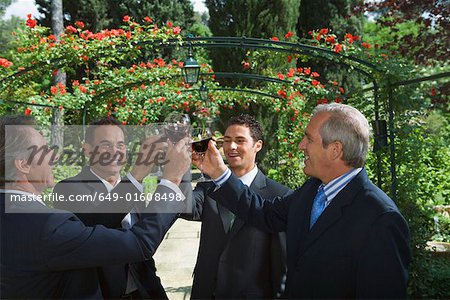 Four businessmen drinking wine in a garden