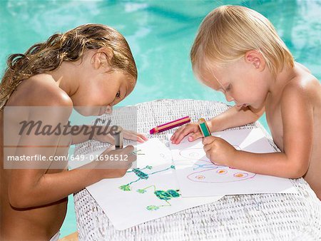 Two young children coloring by a pool.