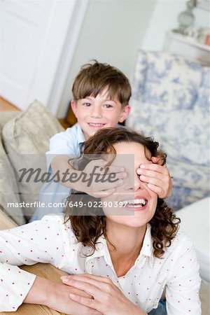 Boy holding the eyes of his mum closed