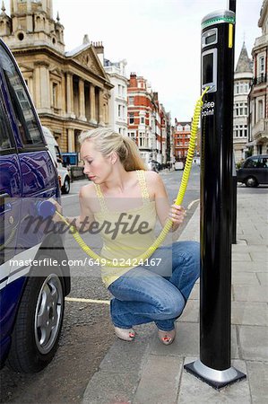 Young woman charging electric car