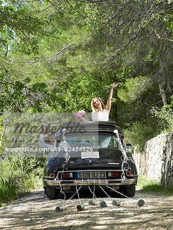 Bride and groom waving from wedding car
