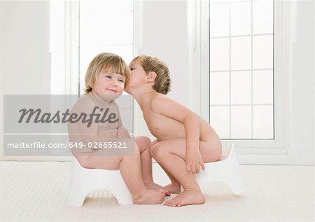 Two toddlers sitting on potties.