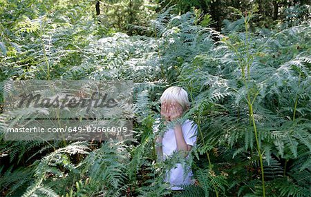 Boy hiding in ferns