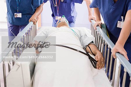 Three doctors pushing a patient in bed