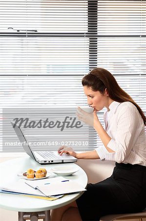 Woman sitting with laptop at cafe table