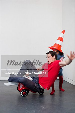 young girl teaching man to ride toy car