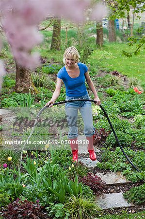 woman watering plants with hose