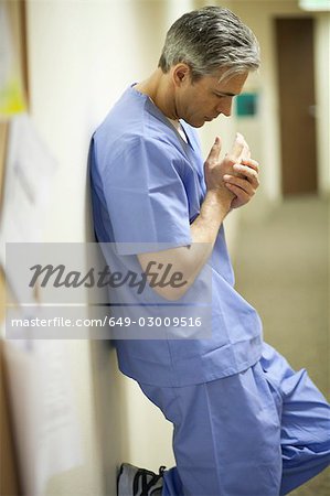 Tired Male surgeon leaning on wall