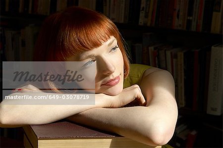woman leaning on pile of books