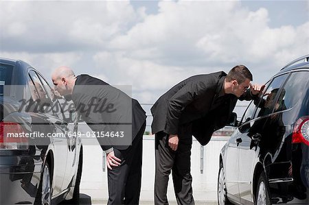 two business men glancing in car