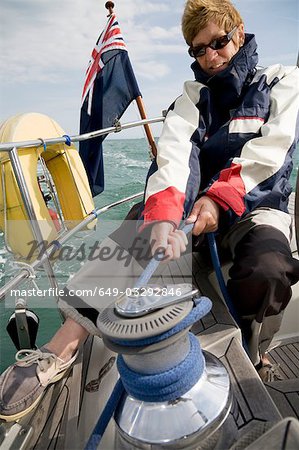 Woman hoisting sails on yacht