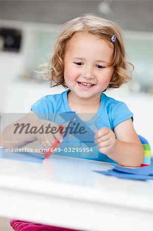 young girl using paper and scissors