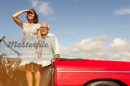 Senior couple with sports car, observing