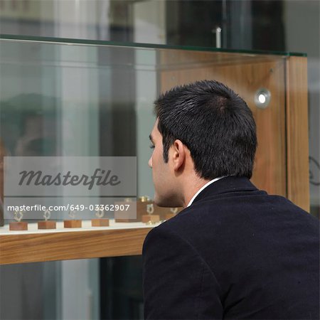 man looking at jewelry in shop window