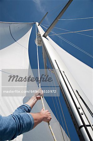 Man pulling ropes on yacht