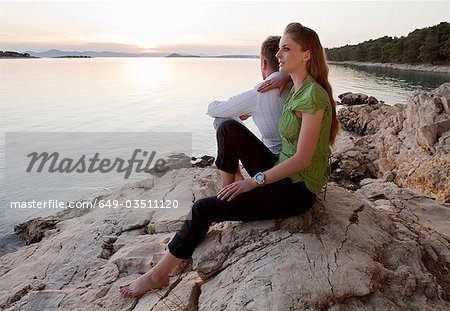 Couple watching sun set at rocky beach