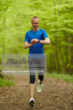 Man running, looking at sports watch