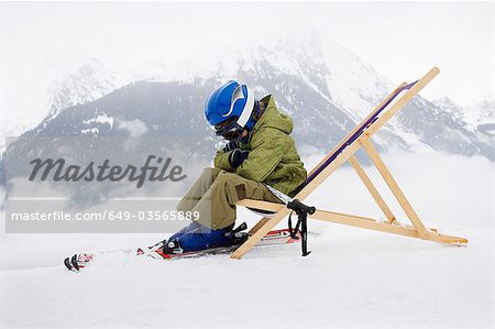 Child with skis sitting on deck chair