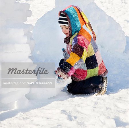 boy building igloo in the snow