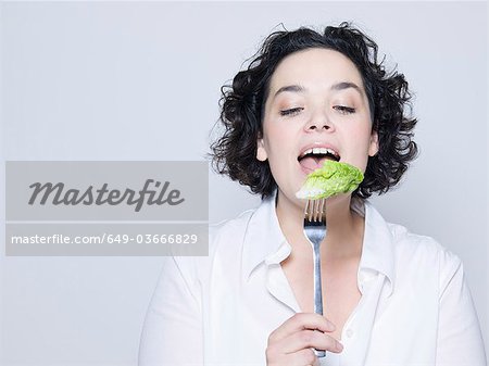 woman holding fork with leaf of salad