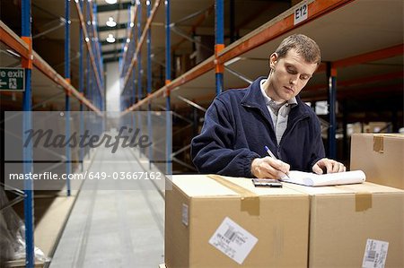 Worker filling in paperwork in warehouse