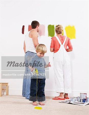 Toddler boy pouring paint on carpet