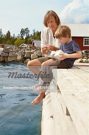 Grandmother and boy fishing from jetty