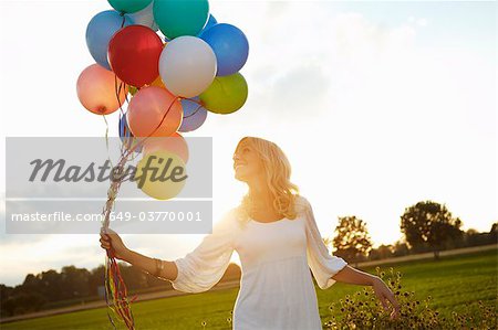 Girl with balloons outside at sunset