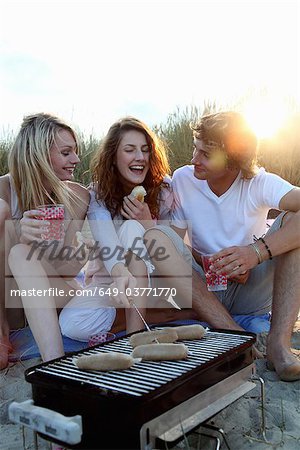 Friends having a beach BBQ at sunset