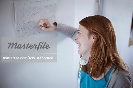 Girl on telephone writing on calendar