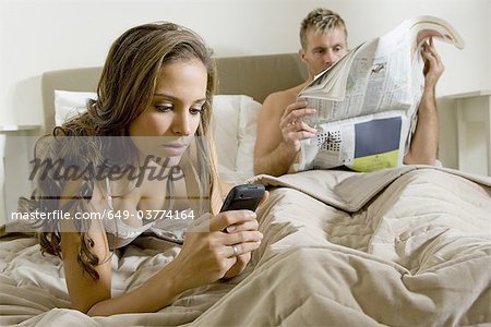 Young woman using smart phone on bed