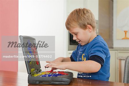Boy playing with paint on laptop