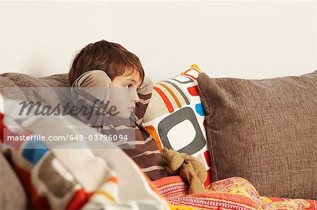 Boy sitting on sofa staring at tv