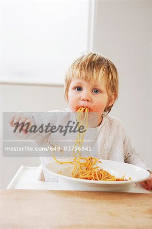 Messy baby boy eating spaghetti