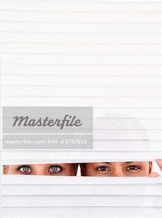 Two women look through blinds