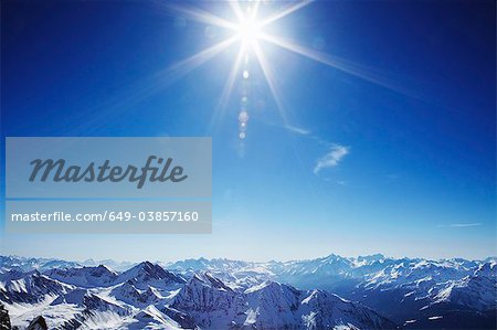 Sun over snow covered mountains
