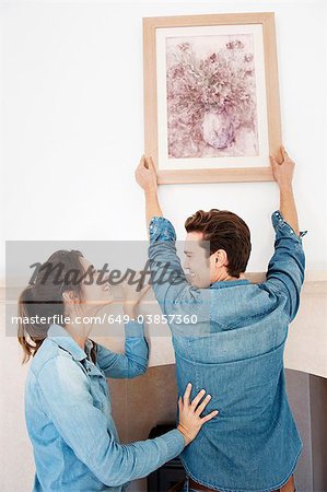 Couple hanging picture in new home