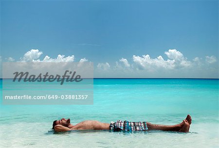 Man floating in water at tropical beach