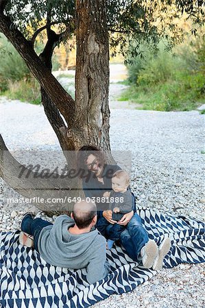 Family relaxing under tree together