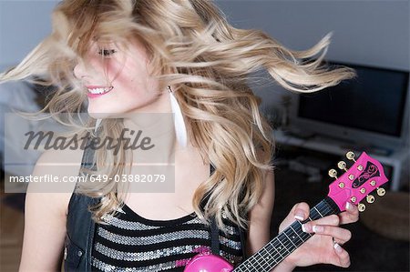 Teenage girl holding miniature guitar