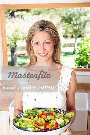 Woman holding salad in kitchen