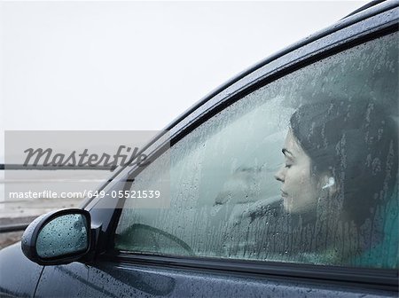 Teenage girl sitting in car by beach