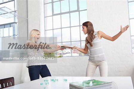 Businesswomen fighting over papers Businesswomen fighting over papers