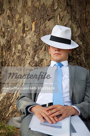 Businessman napping on tree in park