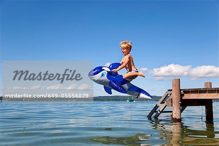 Boy jumping into lake with toy whale