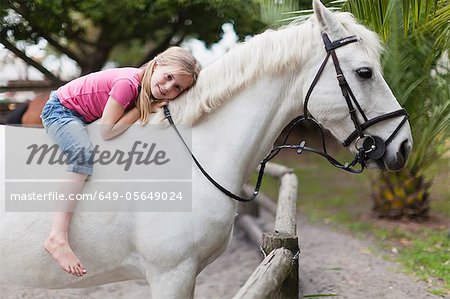Smiling girl riding horse in yard